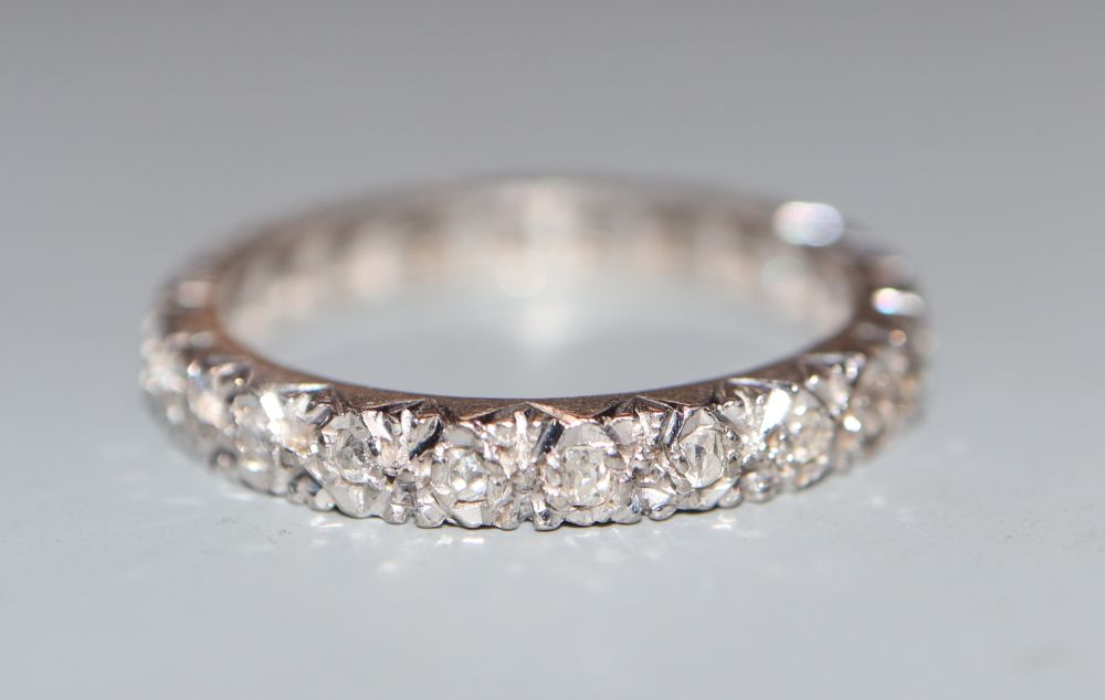 A white metal (stamped 18) and diamond chip set full eternity ring, size L/M, gross 3 grams.